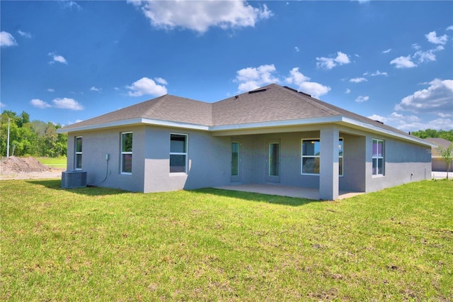 rear view of property with a lawn, cooling unit, and a patio area