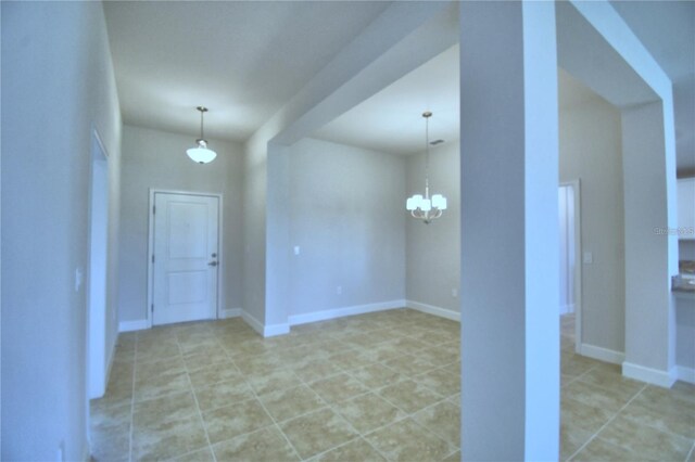 empty room with an inviting chandelier and light tile patterned floors