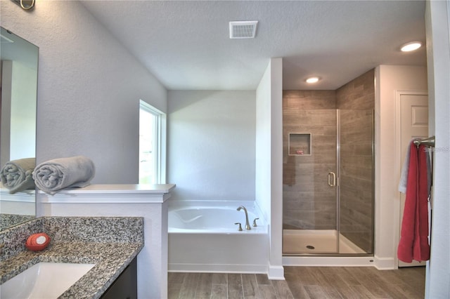 bathroom with wood-type flooring, a textured ceiling, separate shower and tub, and vanity