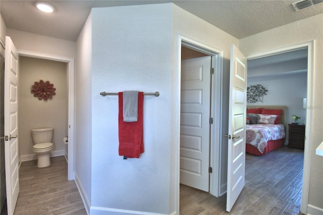 bathroom featuring wood-type flooring, a textured ceiling, and toilet