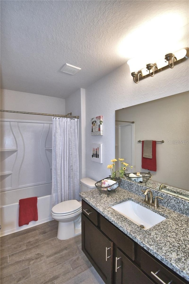 full bathroom with shower / bath combo, wood-type flooring, toilet, a textured ceiling, and vanity