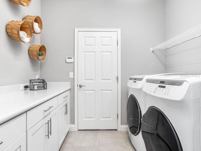 washroom with washing machine and dryer and cabinets