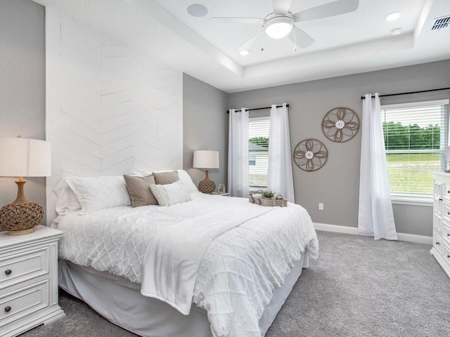 bedroom with carpet flooring, ceiling fan, and a raised ceiling