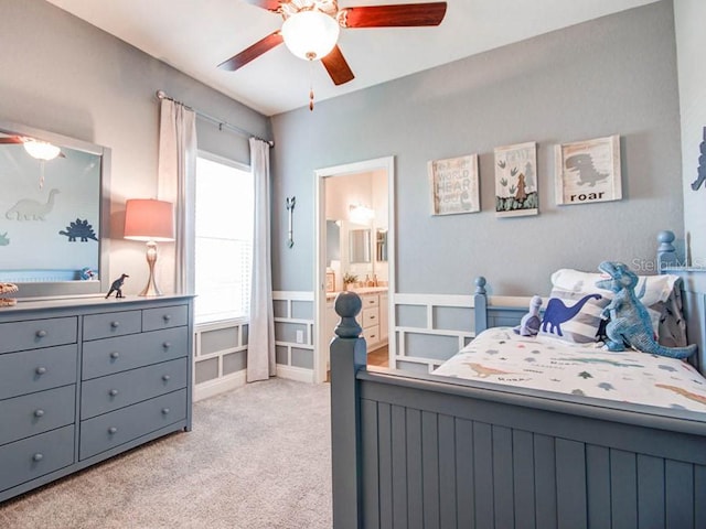 carpeted bedroom with ensuite bathroom and ceiling fan