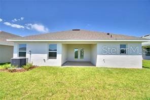 back of property featuring a lawn and central AC