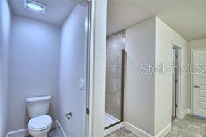 bathroom featuring toilet and a tile shower