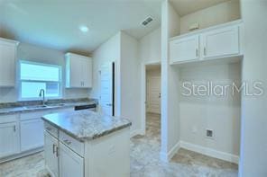 kitchen with white cabinetry, sink, and a kitchen island