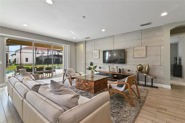 living room with light wood-type flooring and a textured ceiling