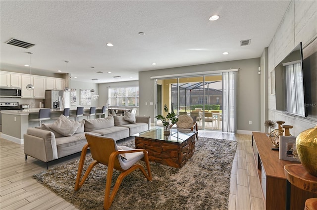 living room with a textured ceiling and light hardwood / wood-style floors