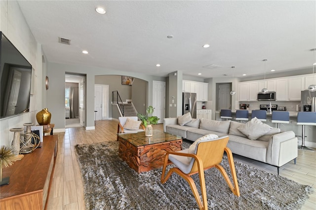 living room featuring light wood-type flooring and a textured ceiling