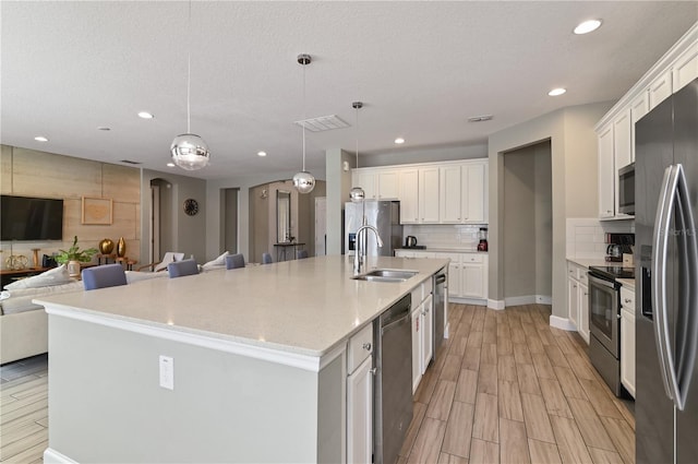 kitchen with white cabinets, a kitchen island with sink, sink, and appliances with stainless steel finishes