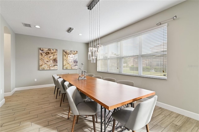 dining space featuring light wood-type flooring and a textured ceiling