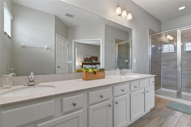 bathroom featuring a shower with shower door and vanity