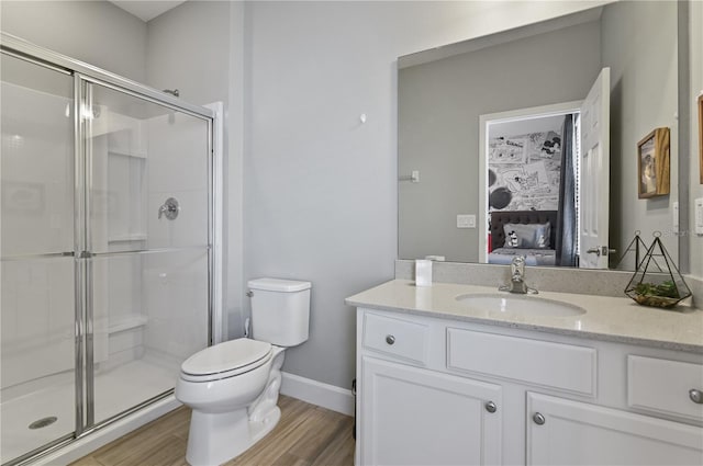 bathroom with hardwood / wood-style floors, walk in shower, vanity, and toilet