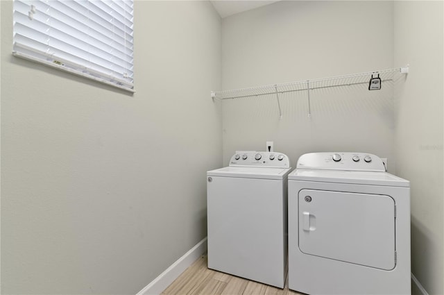 clothes washing area with separate washer and dryer and light hardwood / wood-style flooring