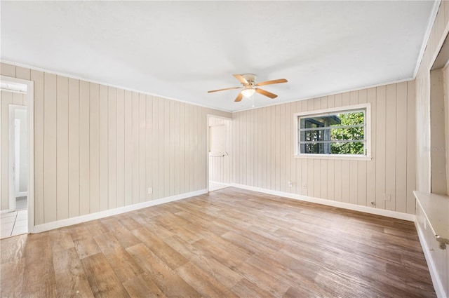 unfurnished room with hardwood / wood-style floors, ornamental molding, ceiling fan, and wooden walls