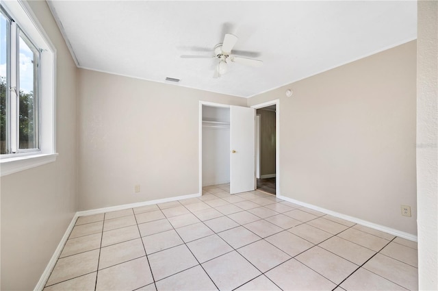 unfurnished bedroom with light tile patterned floors, a closet, ceiling fan, and crown molding