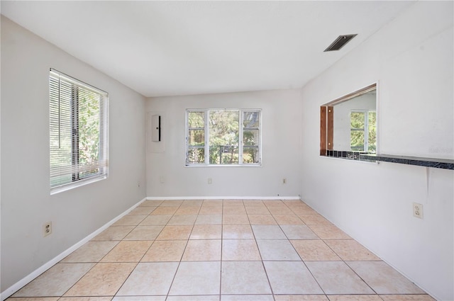 empty room featuring plenty of natural light, light tile patterned floors, and lofted ceiling