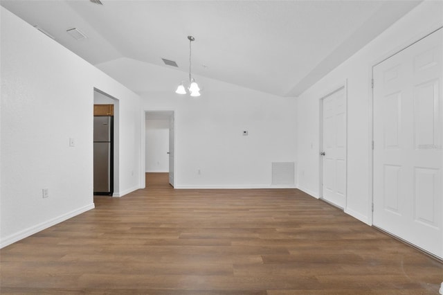 interior space featuring dark wood-type flooring, lofted ceiling, and a notable chandelier