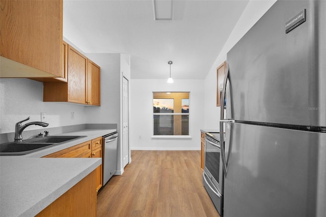 kitchen with hanging light fixtures, sink, light hardwood / wood-style flooring, and appliances with stainless steel finishes