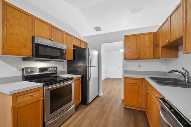 kitchen with stainless steel appliances, lofted ceiling, sink, and light hardwood / wood-style flooring