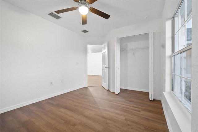 unfurnished bedroom featuring multiple windows, dark hardwood / wood-style floors, and ceiling fan