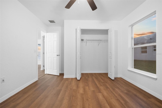 unfurnished bedroom featuring hardwood / wood-style floors, ceiling fan, and a closet