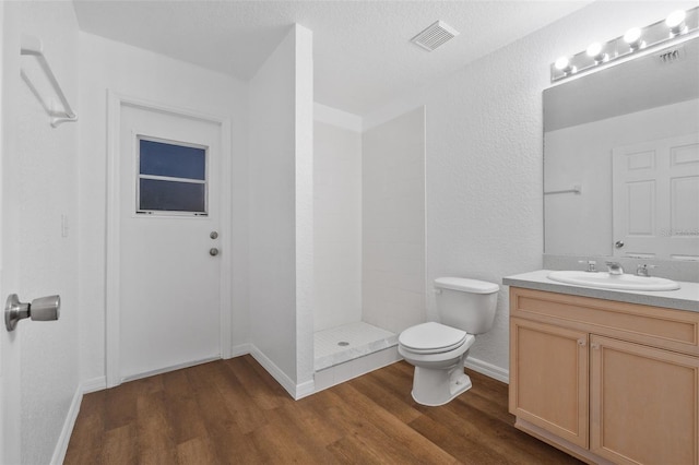 bathroom with hardwood / wood-style floors, vanity, toilet, and a shower