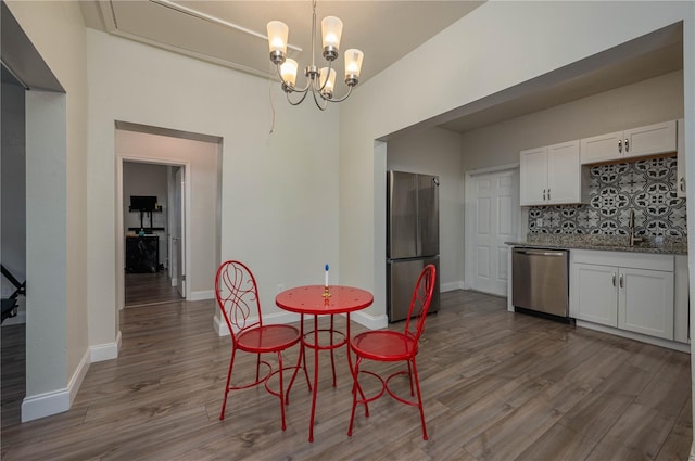 dining space with sink, a notable chandelier, and light wood-type flooring