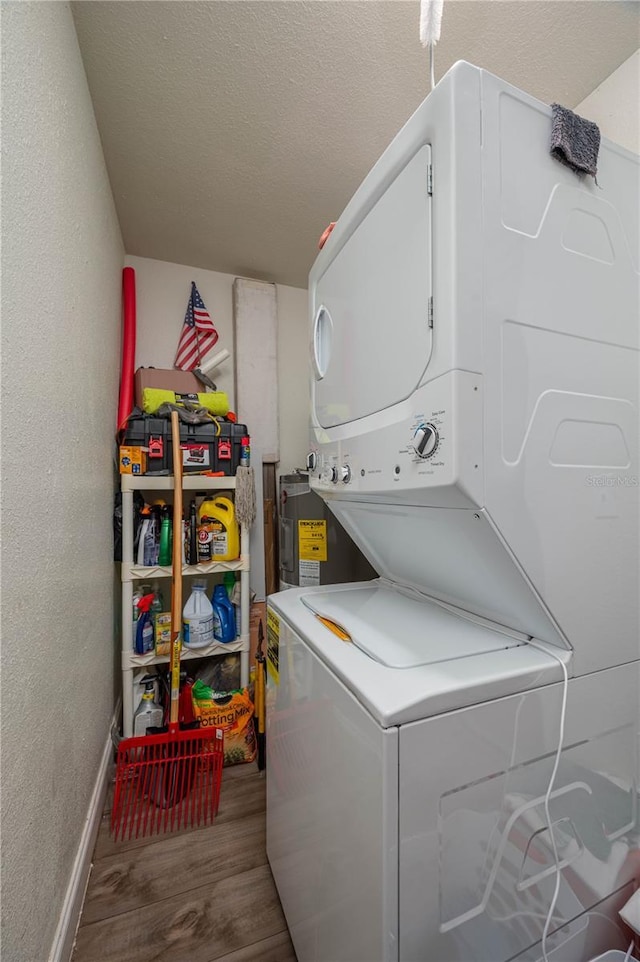 washroom featuring a textured ceiling, stacked washer and clothes dryer, and wood-type flooring