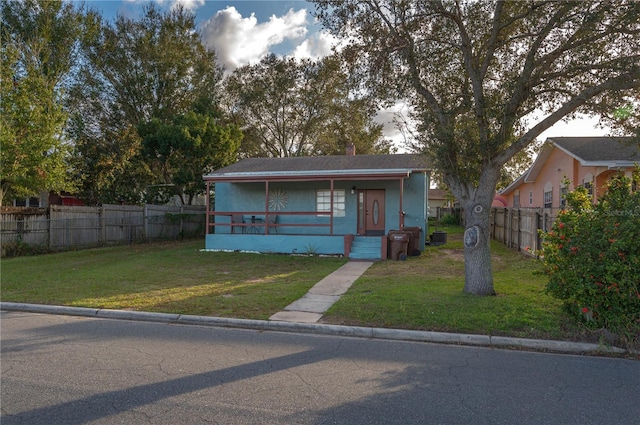 view of front facade featuring a chimney, a porch, a front lawn, and fence