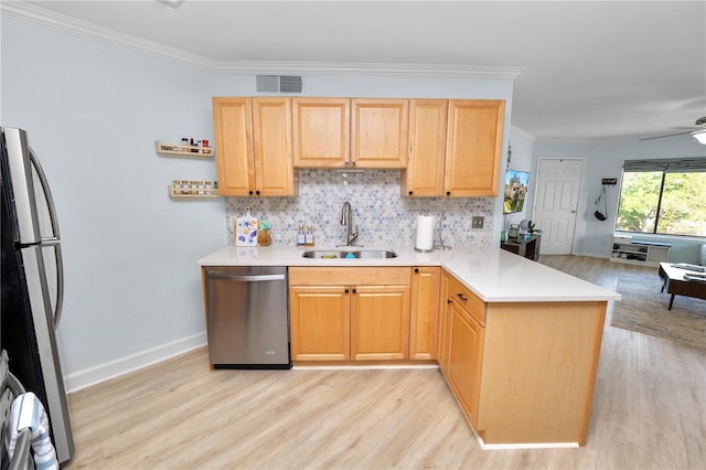 kitchen featuring sink, stainless steel appliances, tasteful backsplash, light brown cabinetry, and kitchen peninsula