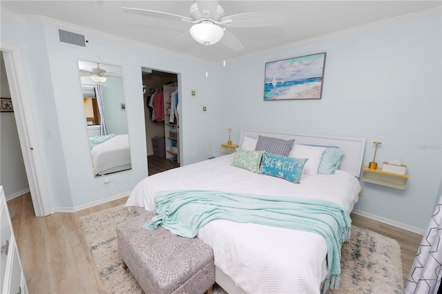 bedroom with crown molding, light hardwood / wood-style flooring, a closet, and a spacious closet