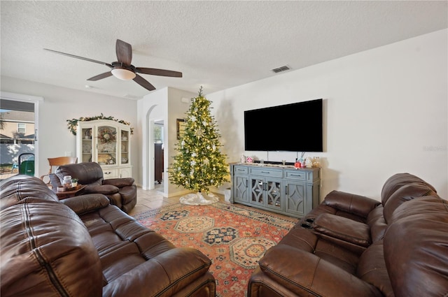 living room featuring ceiling fan, light tile patterned floors, and a textured ceiling