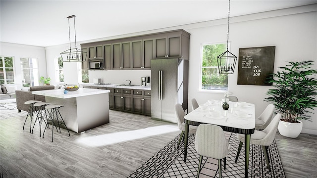 kitchen with a center island with sink, sink, appliances with stainless steel finishes, decorative light fixtures, and light hardwood / wood-style floors