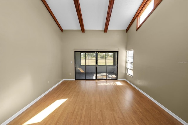 empty room with a towering ceiling, beam ceiling, and light wood-type flooring