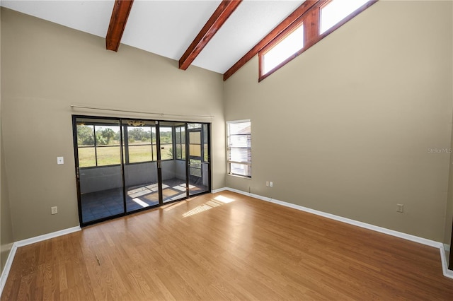 unfurnished room featuring hardwood / wood-style floors, beamed ceiling, and a high ceiling