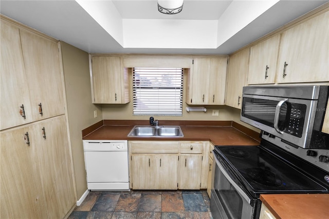 kitchen featuring stainless steel appliances, sink, light brown cabinets, and a tray ceiling