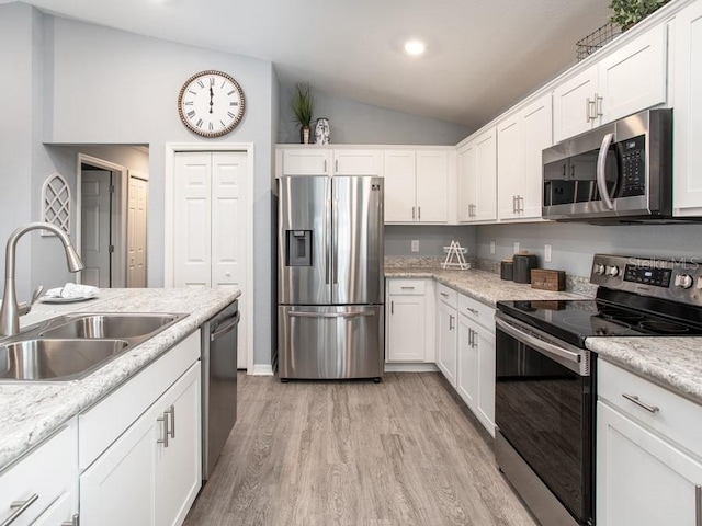 kitchen with stainless steel appliances, white cabinets, sink, and vaulted ceiling