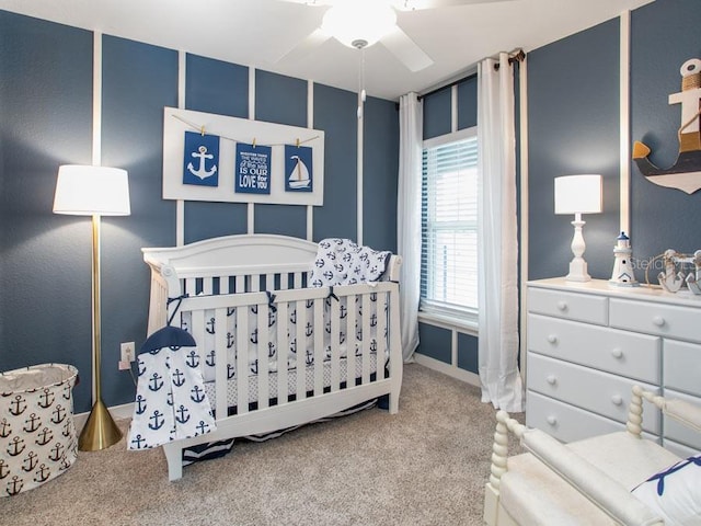 carpeted bedroom with a crib and ceiling fan