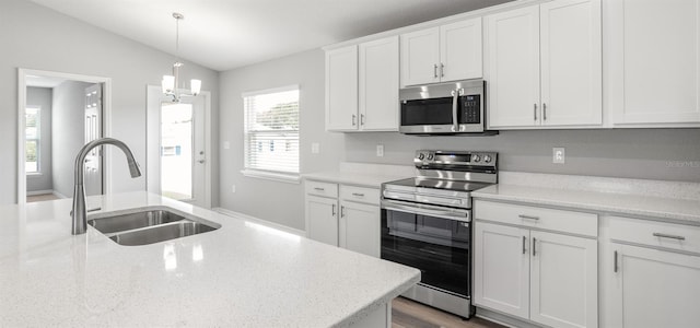 572 SW 77th Cir, Ocala, FL 34480 - kitchen featuring appliances with stainless steel finishes, a sink, vaulted ceiling, white cabinets, and pendant lighting
