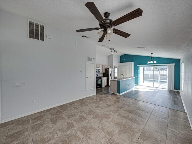 unfurnished living room with ceiling fan with notable chandelier, a textured ceiling, light hardwood / wood-style floors, and vaulted ceiling