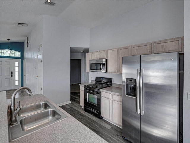 kitchen featuring appliances with stainless steel finishes, light brown cabinets, hanging light fixtures, and sink