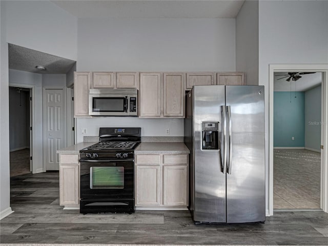 kitchen with ceiling fan, dark hardwood / wood-style flooring, light brown cabinetry, and appliances with stainless steel finishes