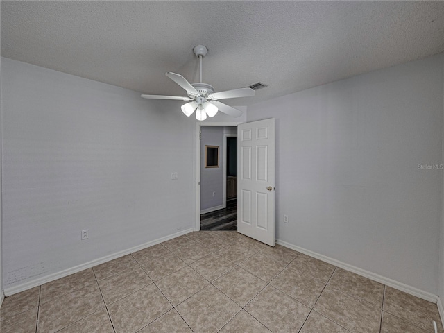 tiled spare room featuring a textured ceiling and ceiling fan