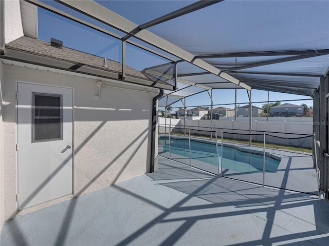 view of swimming pool featuring glass enclosure and a patio