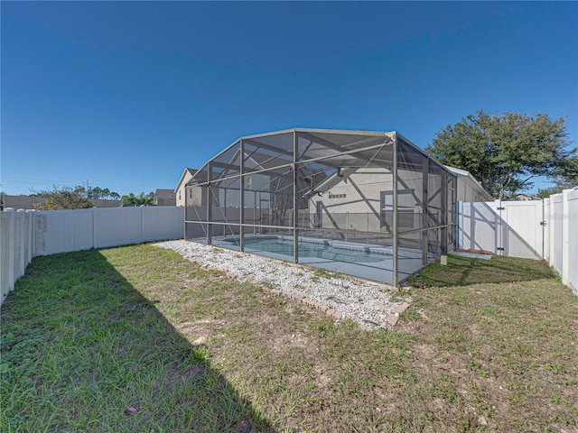 back of house featuring a lawn, a lanai, and a fenced in pool