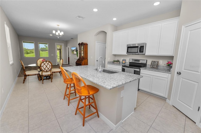 kitchen featuring white cabinetry, sink, light stone counters, an island with sink, and appliances with stainless steel finishes