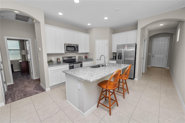 kitchen with white cabinets, stainless steel appliances, a center island with sink, and sink