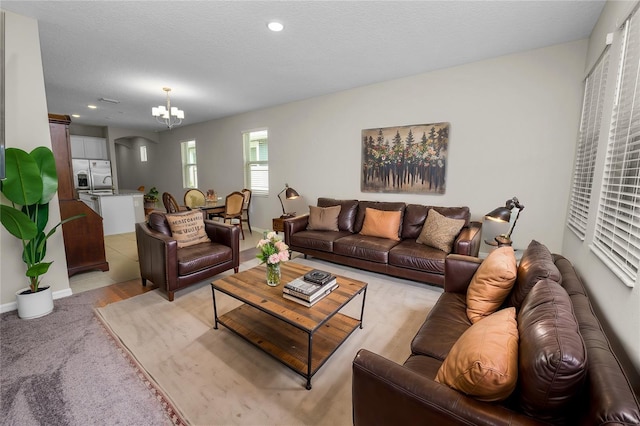 living room featuring light carpet, a chandelier, and a textured ceiling